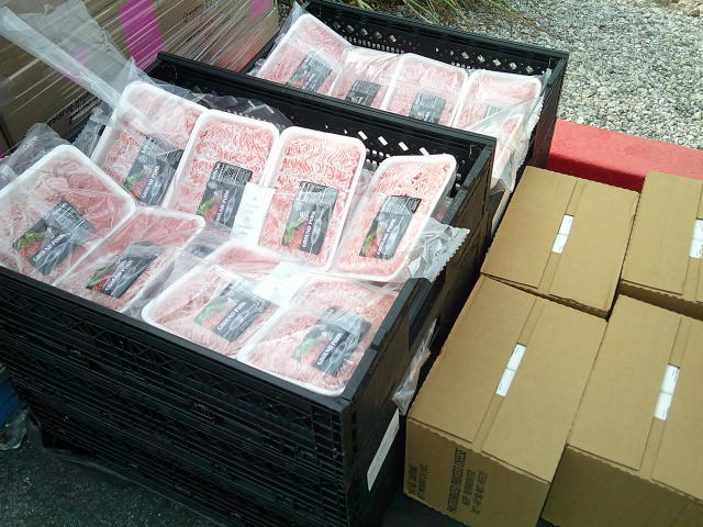 Crates filled with pork next to boxes of cheese.
